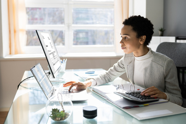 Work from home employee sitting at desk with monitors