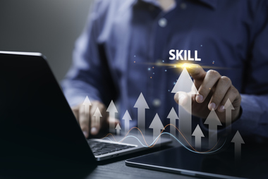 The word Skill sitting on top of graphic arrows pointing up from laptop